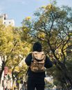 一个穿着黑色连帽衫、背着背包的人，独自在背景模糊的树林中行走