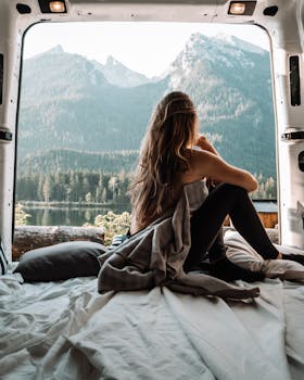 A woman enjoying a peaceful moment inside a campervan with a stunning mountain view, embracing the van life and nature.