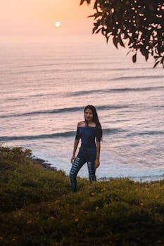 A woman stands by the coast in Lima with a breathtaking view of the Pacific Ocean at sunset.