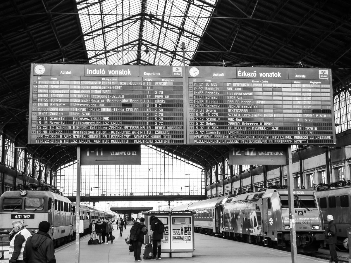 A busy train station with a prominent departure board and commuters passing through