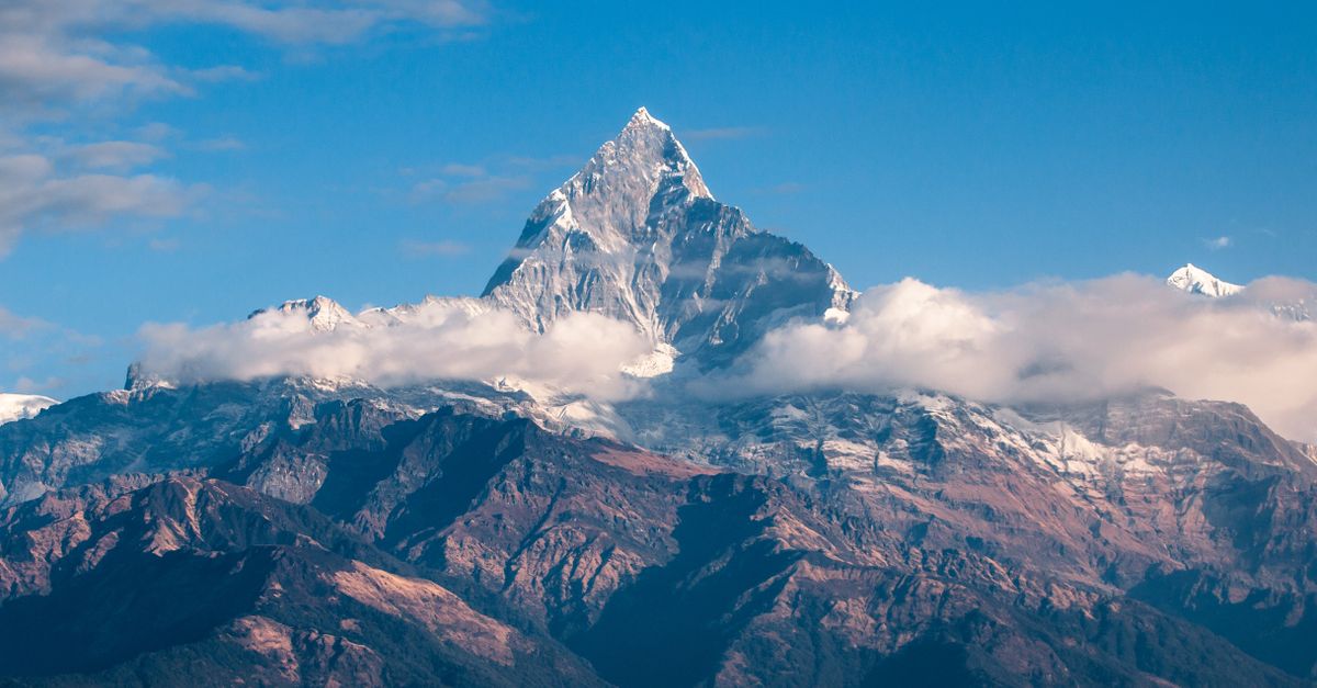Rüyada Dağ Zirvesinde Olmak - Rüya Tabiri ve Anlamı - Breathtaking view of a snow-covered mountain peak surrounded by clouds during sunrise.