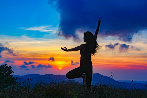 Woman practicing yoga at sunset in the mountains