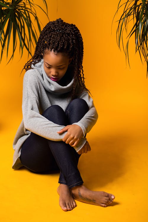 Upset young African American lady resting in yellow room