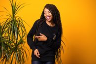 Positive young African American woman looking away and smiling in yellow studio