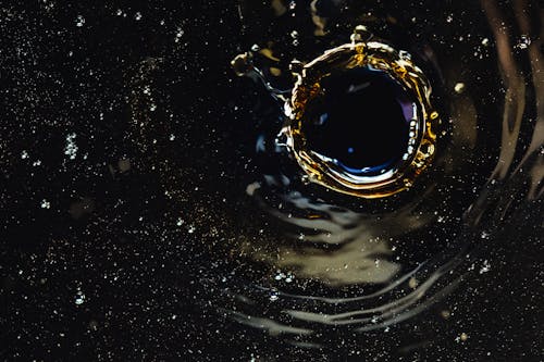 Droplet creating splash in dark liquid