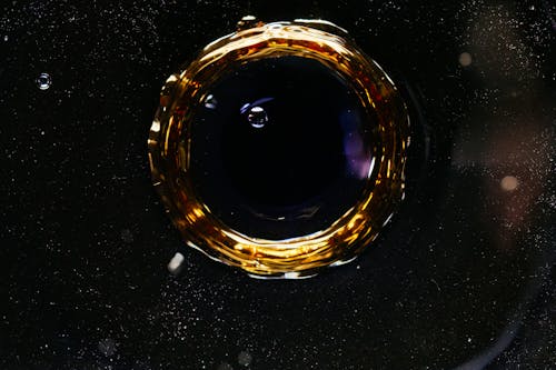 From above of macro drop falling in dark water and forming circle and bubbles as background