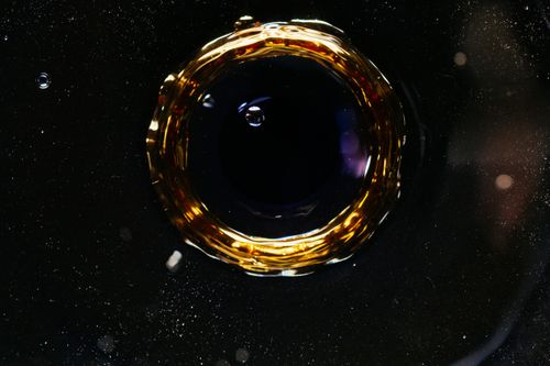 Free From above of macro drop falling in dark water and forming circle and bubbles as background Stock Photo