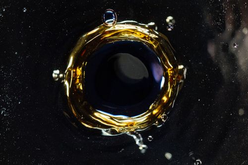 Free Closeup of droplet hitting surface of dark liquid and creating round shaped swirl and splashes as background Stock Photo