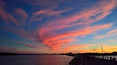 泽西市海滨上空的日落景色令人惊叹，色彩缤纷的云彩和平静的河流构成了一幅充满活力的画面