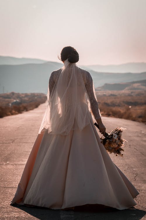 Free A Woman in White Wedding Dress Standing on the Road Stock Photo