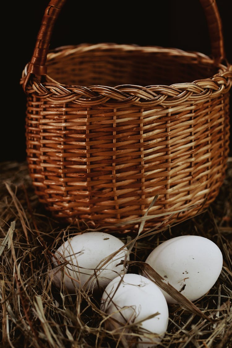 White Chicken Eggs In Nest Near Wicker Basket