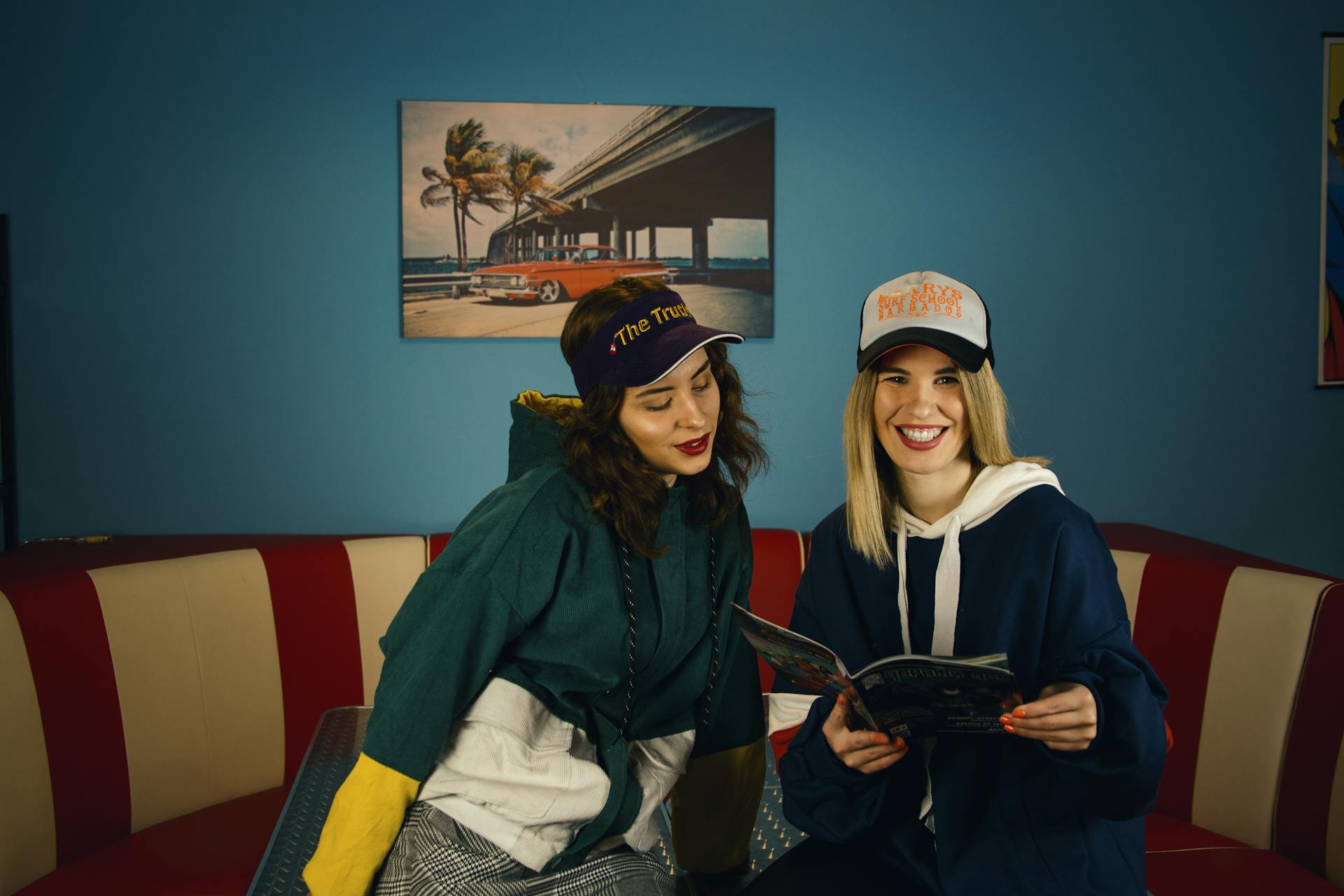 Cheerful young women reading magazine in retro diner