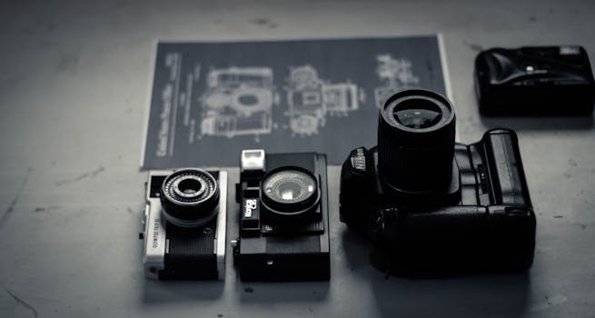 A collection of vintage and modern cameras arranged on a desk indoors.