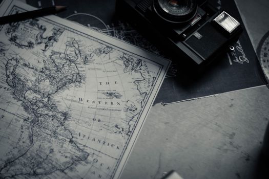 Black and white vintage photo camera and paper map composing with pen and protractor on table in bright room