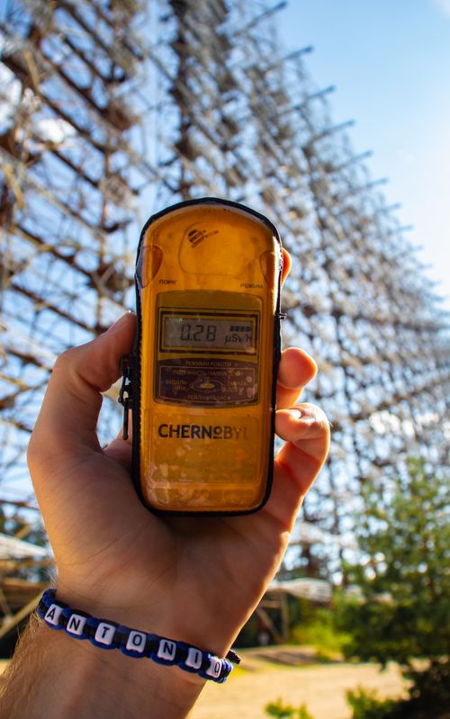 Free Hand holding a dosimeter measuring radiation level at Chernobyl with Duga radar in background. Stock Photo