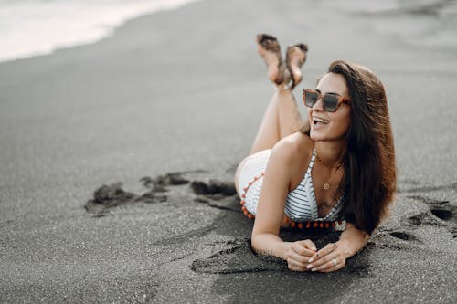 Happy woman lying on wet sand