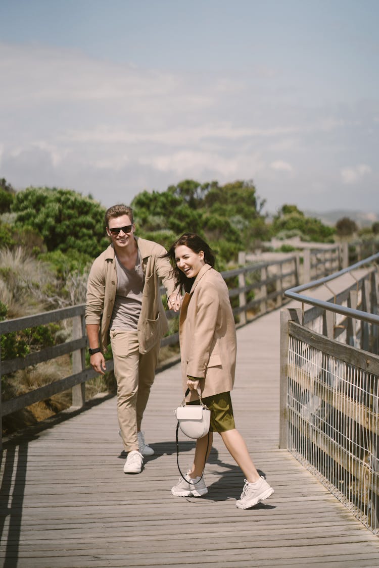 Laughing Couple Walking On Wooden Boardwalk