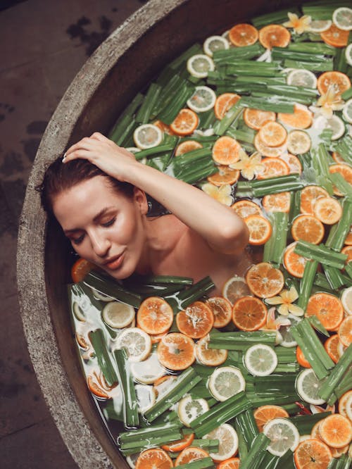 Content woman enjoying exotic bath with citrus fruits