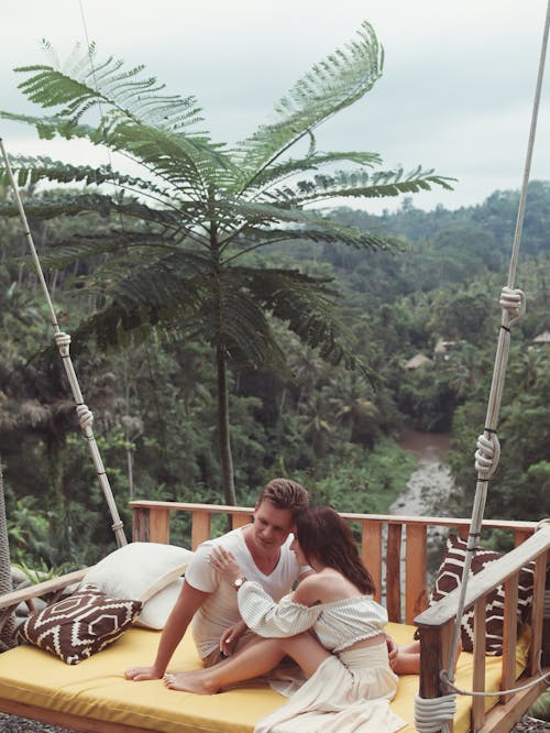 Calm happy couple resting on swing in tropics