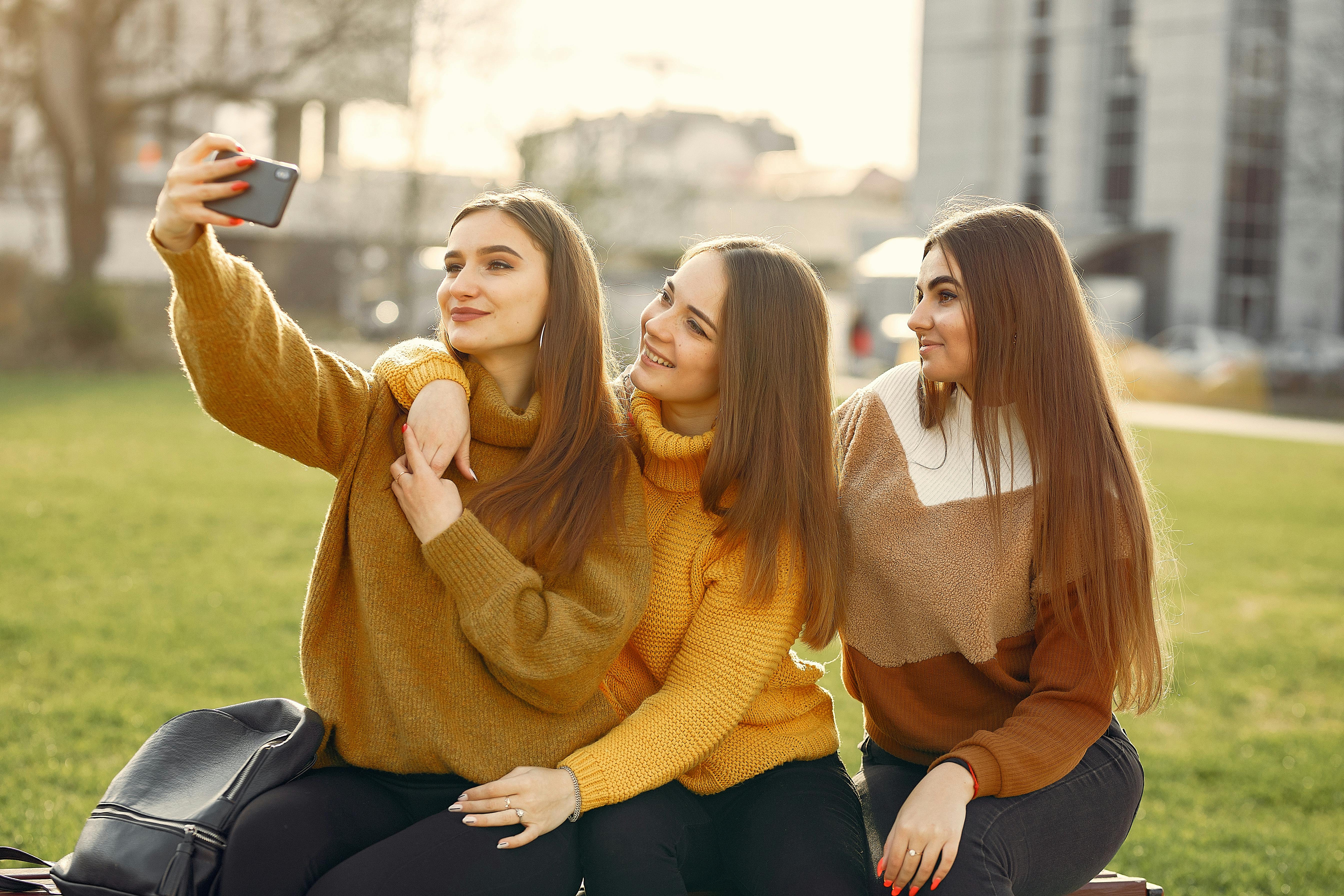 cheerful girlfriends taking selfie on smartphone in park