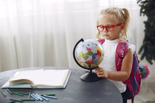 Little girl studying globe at home