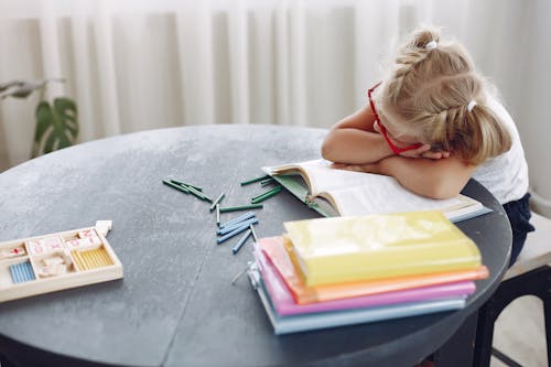 Free Tired little child wearing casual clothes and sleeping on book in living room at home during break during weekend day Stock Photo