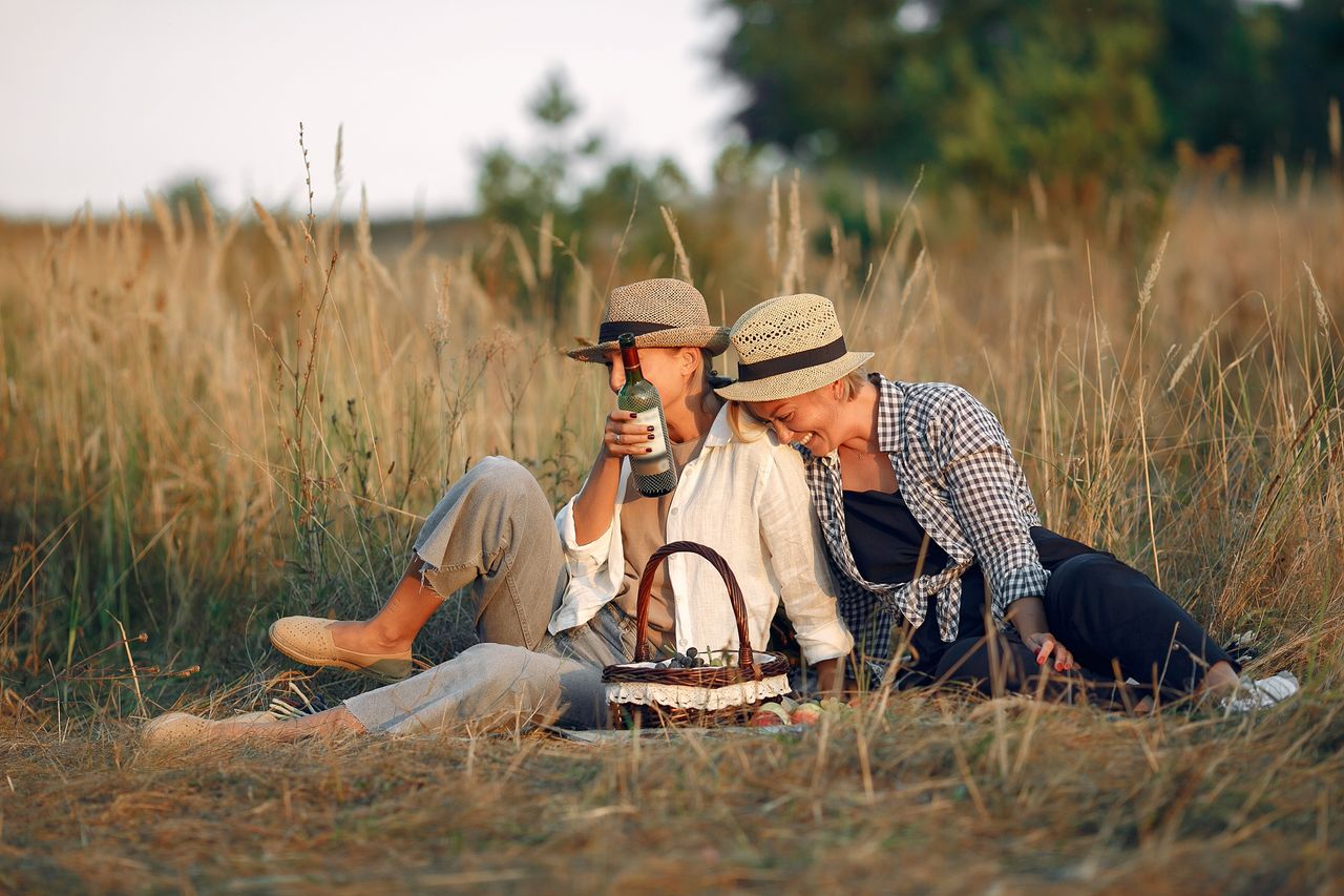 cheerful women in casual clothes and hats laughing while resting with