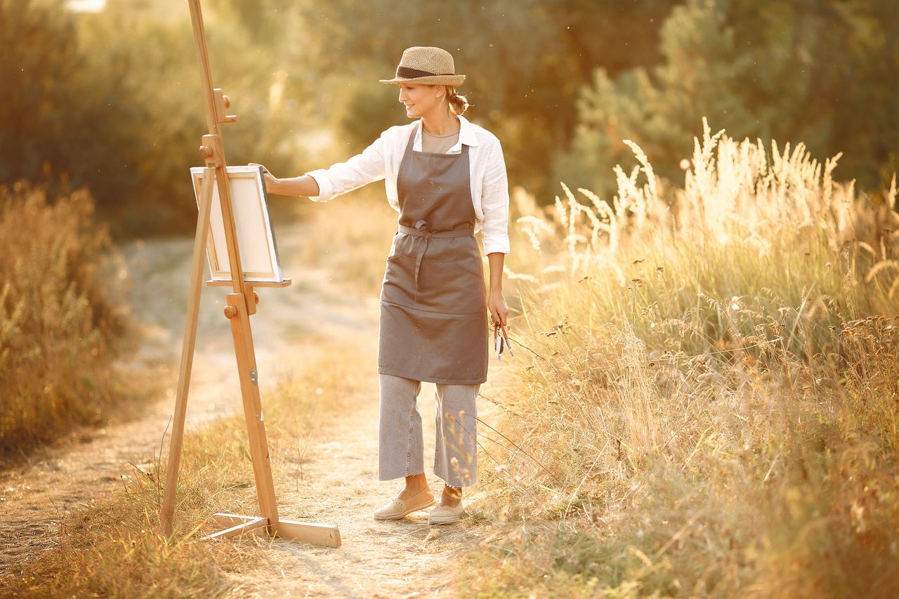 full body of cheerful female wearing hat and apron standing on road in