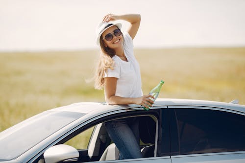 Free Cheerful young woman with refreshing drink in automobile during car trip Stock Photo