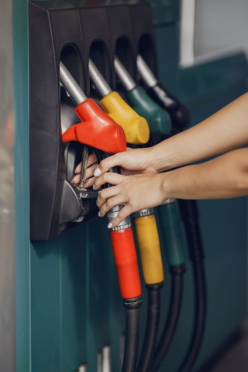 A driver fueling a car at a gas station pump