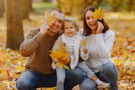 Cheerful family having fun with autumn leaves