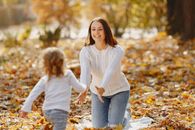 Happy young mother and daughter having fun in autumnal park