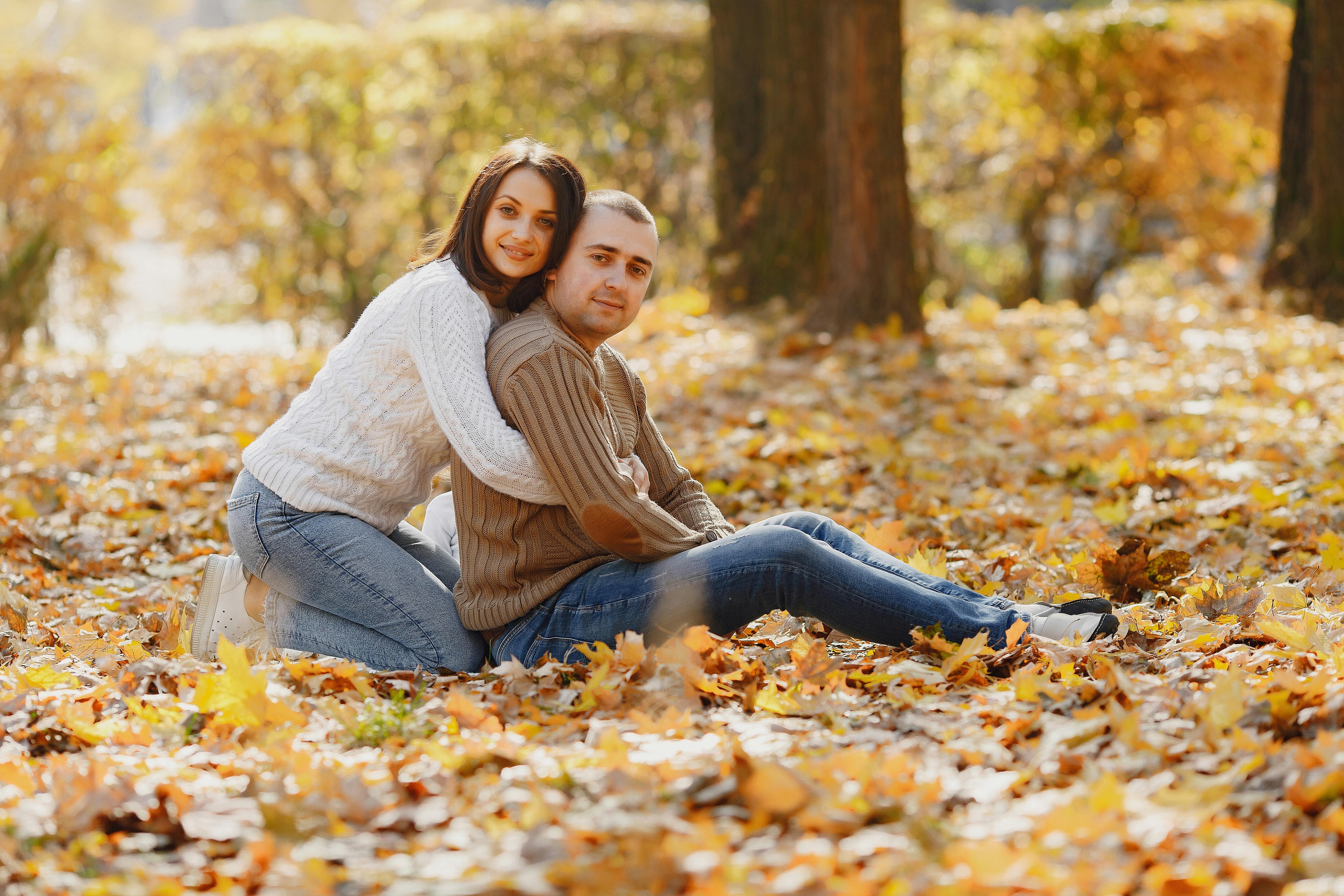 gentle adult couple in warm clothes hugging in autumnal park