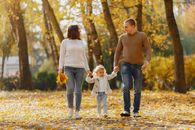 Happy family walking on alley in autumn park