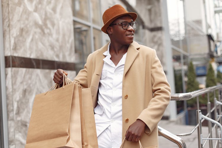 Cheerful Black Man With Shopping Bags On Street