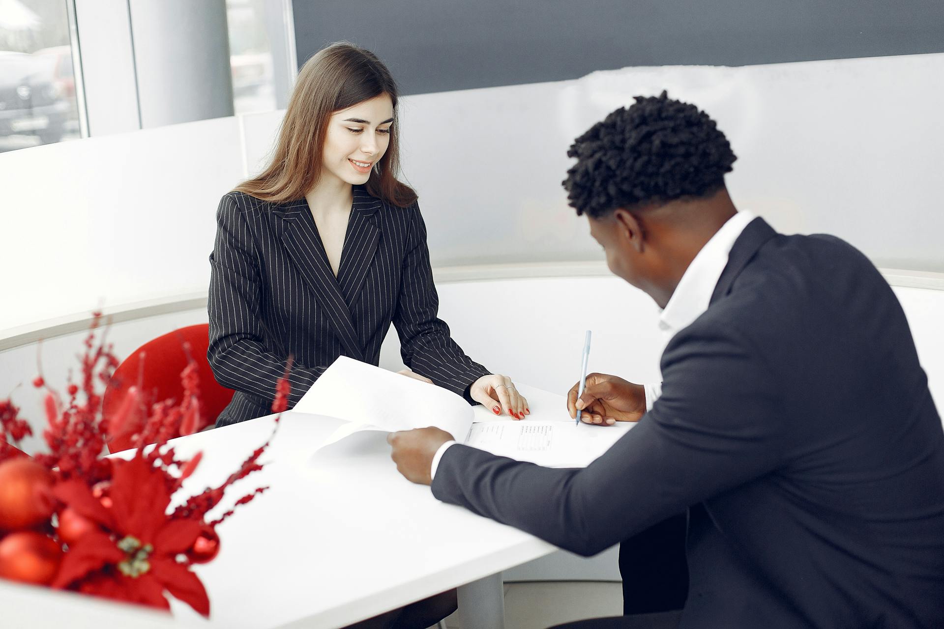 A professional setting with two business people signing a contract in an office environment.