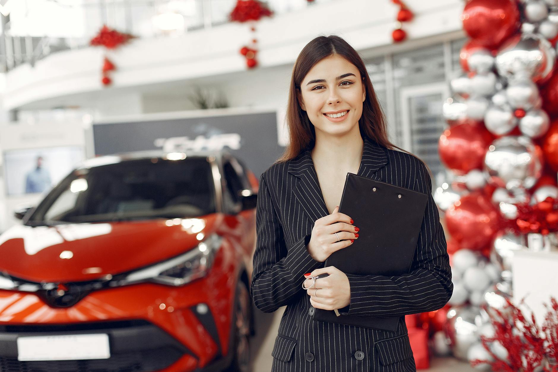 delighted-young-female-car-dealer-in-car-salon-free-stock-photo