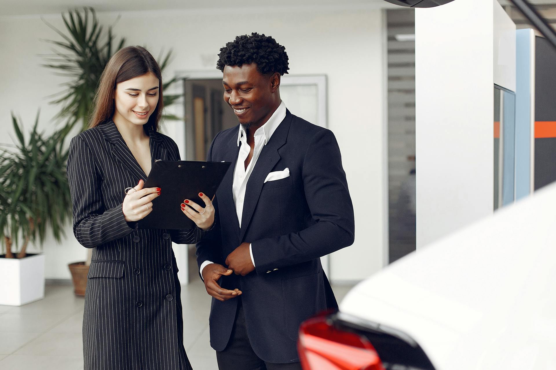 Two professionals discussing options inside a car dealership.