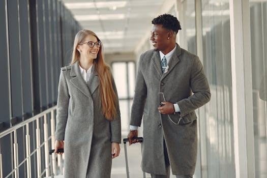 Two smiling business professionals walking in an airport terminal with luggage.