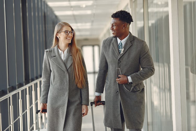 Stylish Colleagues Walking Along Airbridge In Airport