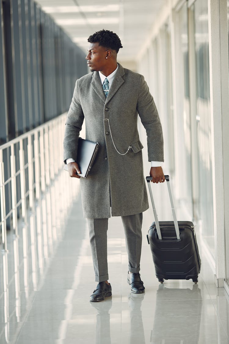 Confident Businessman With Laptop And Suitcase Walking In Airport Hallway