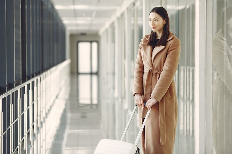 Content Woman With Suitcase Waiting For Boarding In Airport