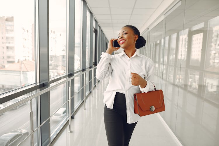 Cheerful Woman Talking On Smartphone In Modern Office Building