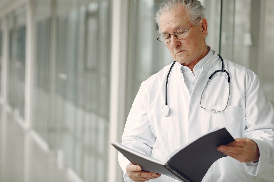 Free Contemplative doctor in uniform reading clinical records Stock Photo