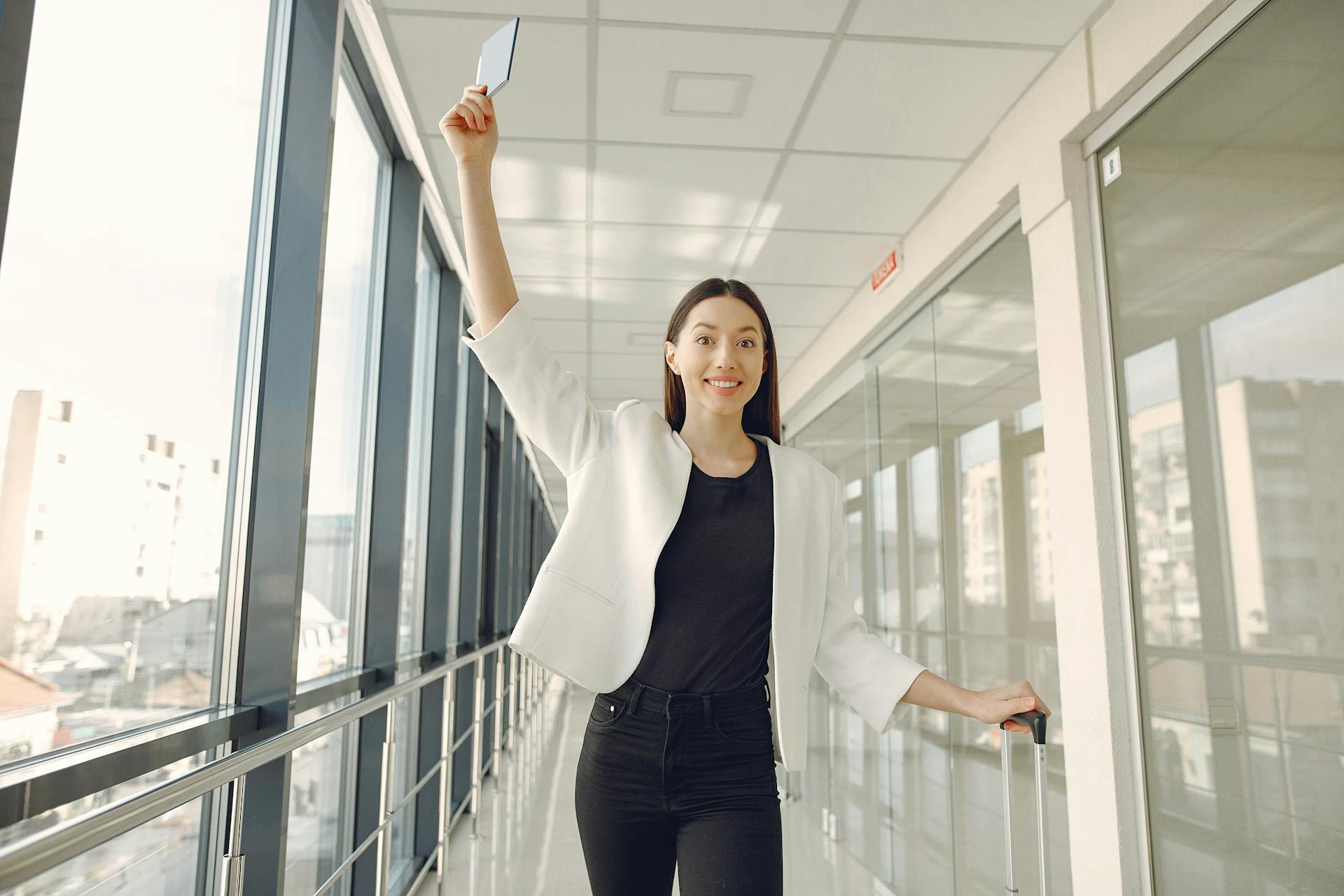 Smiling woman in airport corridor holding a ticket, ready for travel adventure.