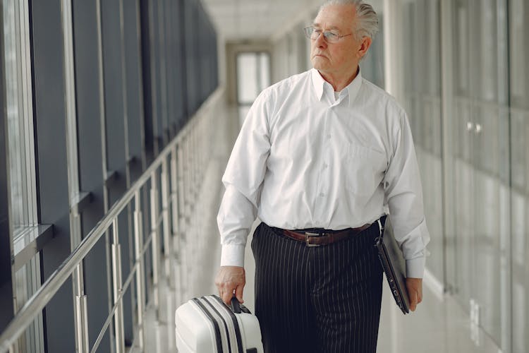 Serious Man With Baggage And Laptop In Airport Corridor