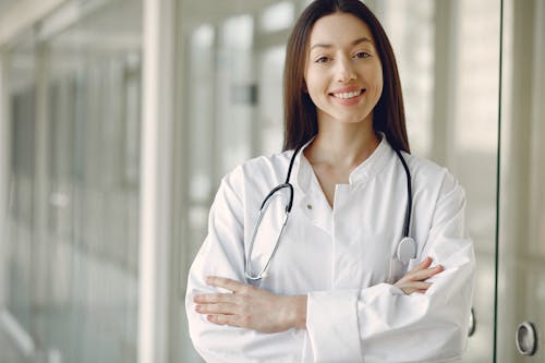 Free Crop doctor in medical uniform with stethoscope standing in clinic corridor Stock Photo