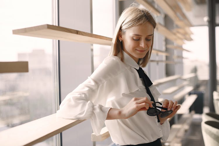 Positive Woman Holding Sunglasses In Office