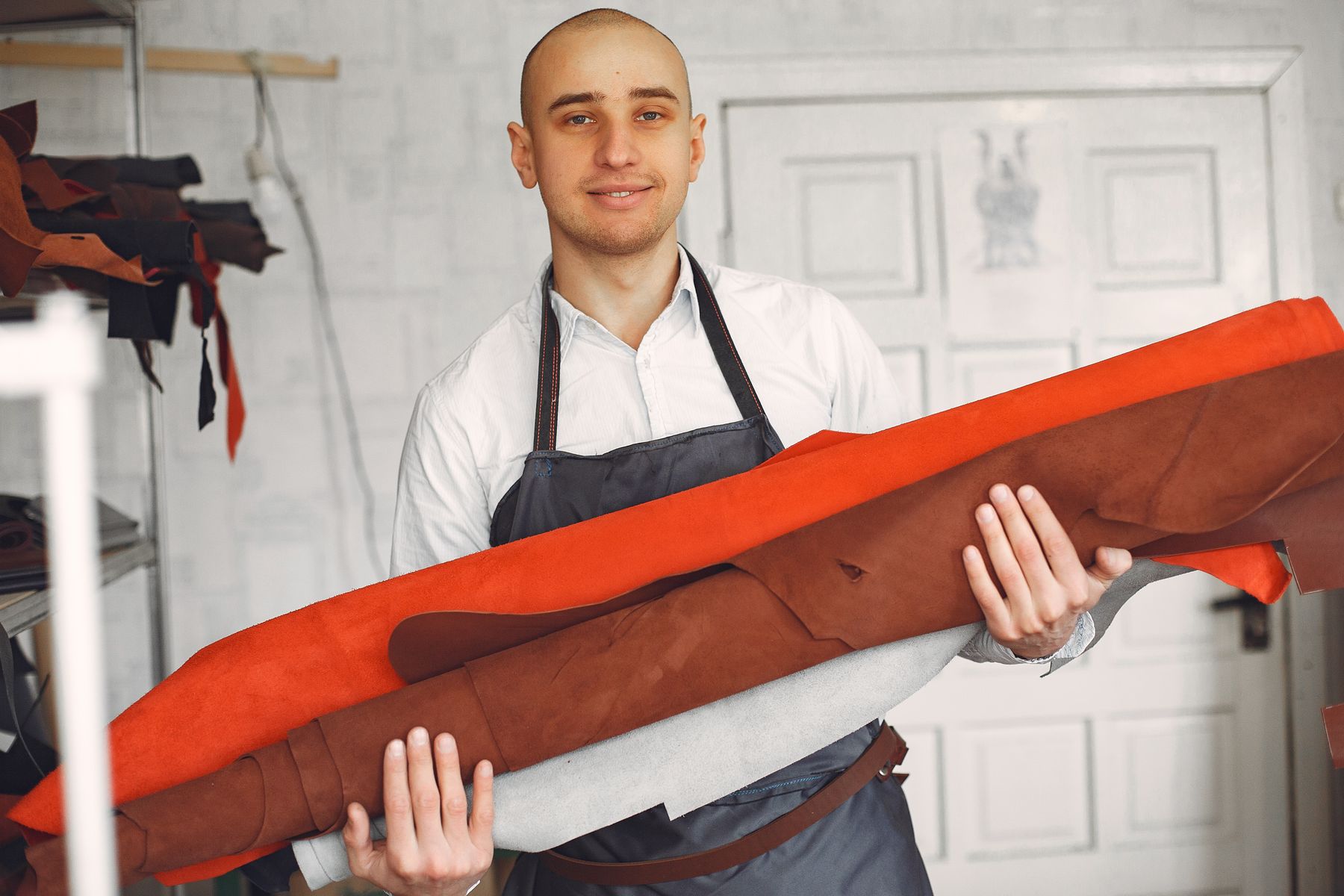 A craftsman holding a roll of leather in his workshop
