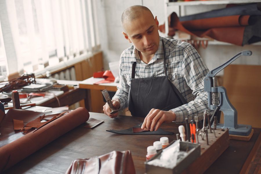 Leather artisan using tools to inspect and finish leather pieces